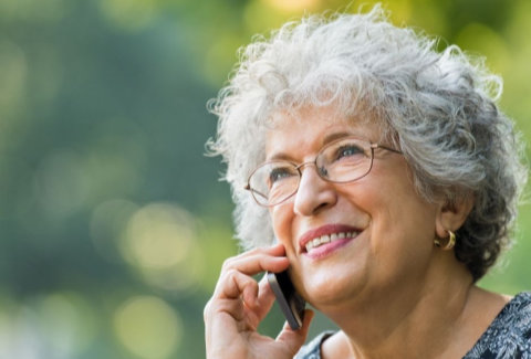 Grey haired woman with glasses on mobile phone