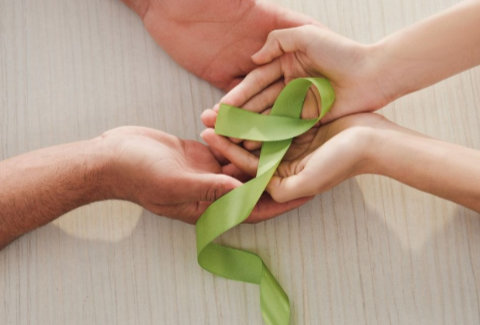 Hands holding a green ribbon