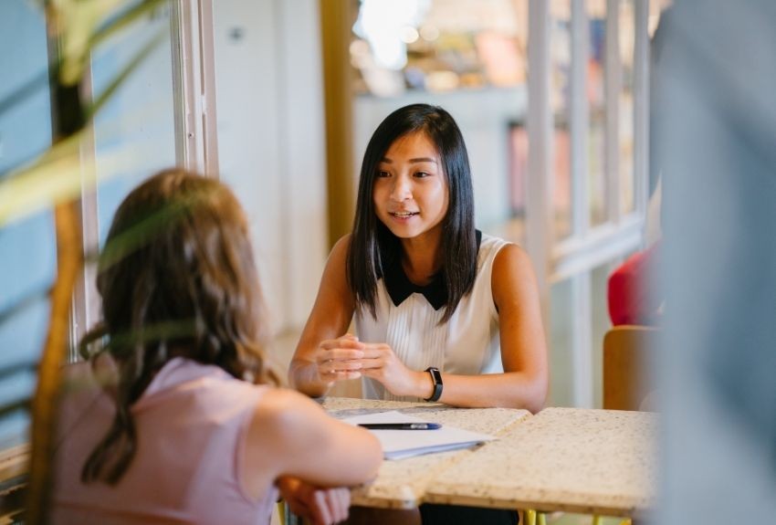 Two people talking sitting across a table from each other