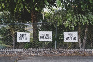 Image of fence with signs saying 'don't give up', 'you are not alone' and 'you matter'