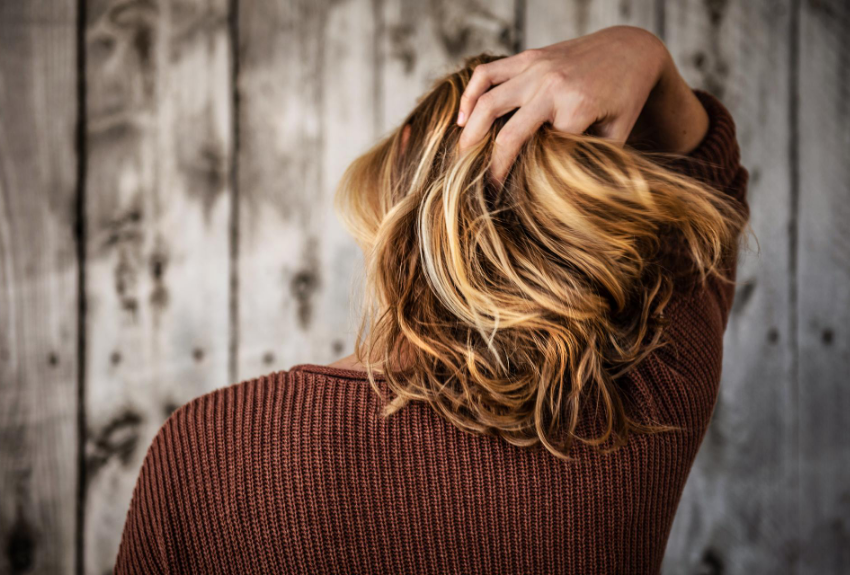 woman-in-brown-jumper-running-fingers-through-her-blonde-hair