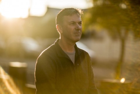 Person looking serious outdoors with setting sun on their back