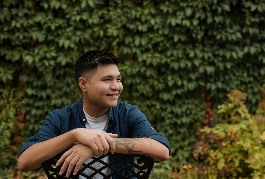 Person sitting in garden smiling and resting arms on the back of their chair