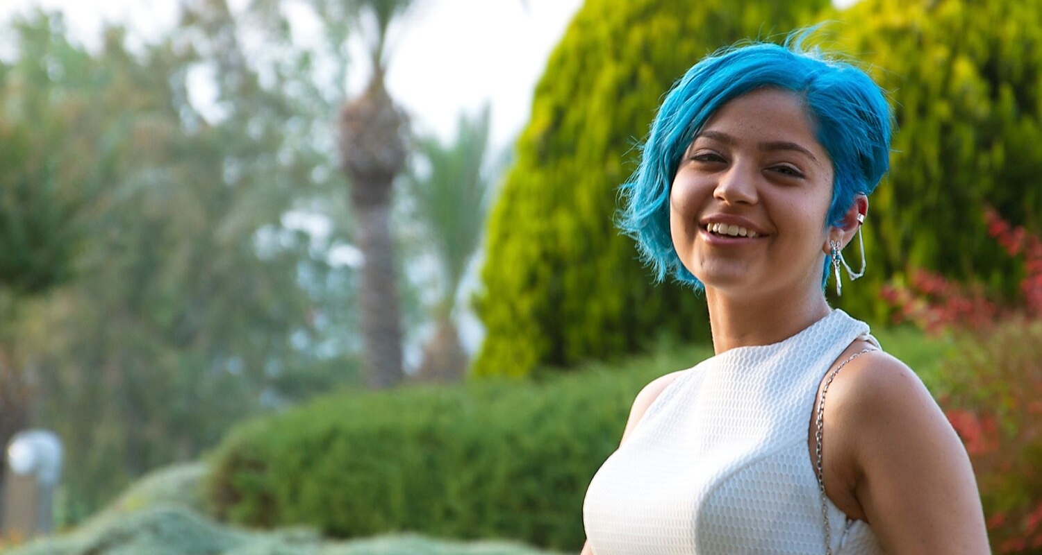 Young woman with blue hair looking happy and hopeful