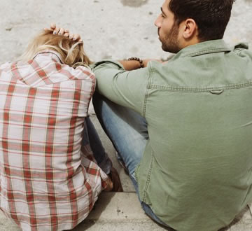 Distressed couple sitting on boardwalk