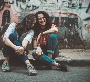 Sisters sitting in front of graffiti