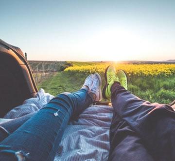 Two people laying down, looking out at flowers and sunrise.jpg