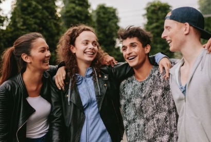 Group of young people linking arms and smiling outside