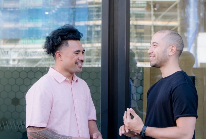 two people talking and smiling outside of a building