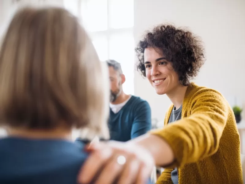 Woman with curly hair providing support in a group counselling session